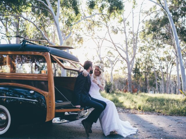 Photo of bride and groom standing beside Sunshine Coast Wedding Classic Car Hire Woody