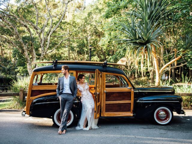 Photo of bride and groom standing beside Sunshine Coast Wedding Classic Car Hire Woody